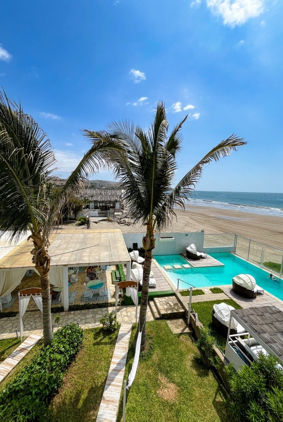 Vista desde la Royal Suite — piscina de Suites del Mar, palmeras y playa de Máncora